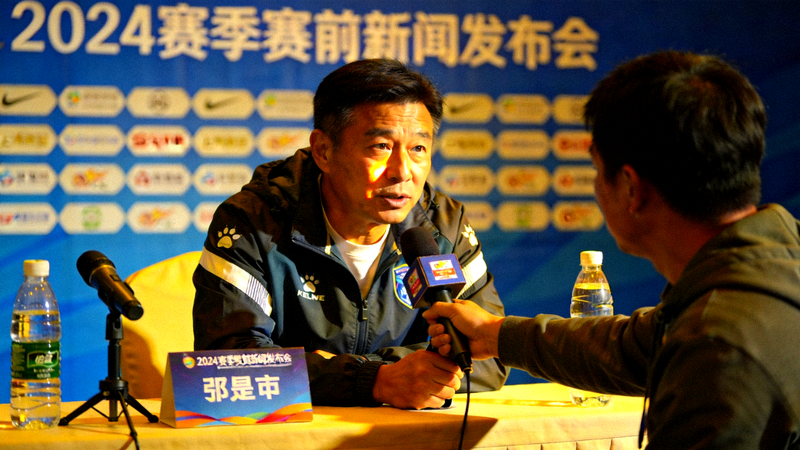 体育新闻发布会现场，教练与记者交流